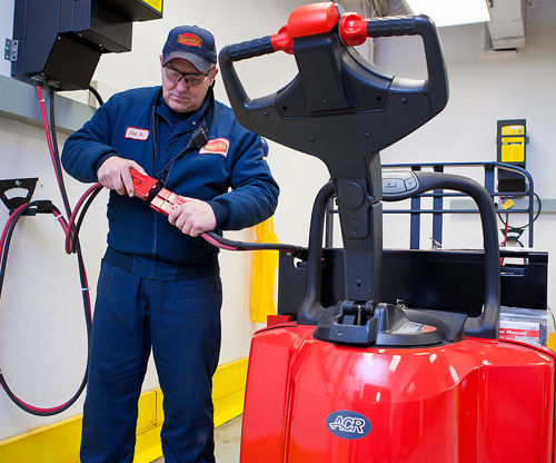 Technician plugging in a forklift to charge battery
